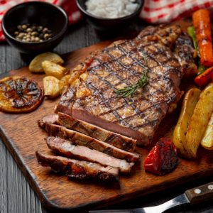 Grilled beef steak on the dark wooden background.